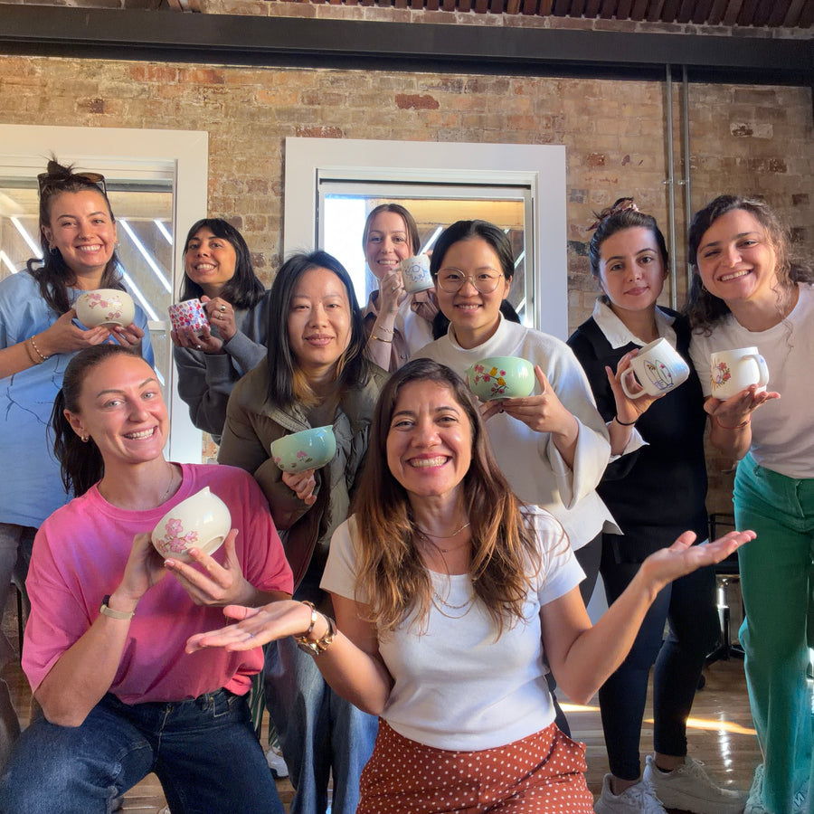 Guests smiling with their hand-painted ceramic bowls at a NOA workshop