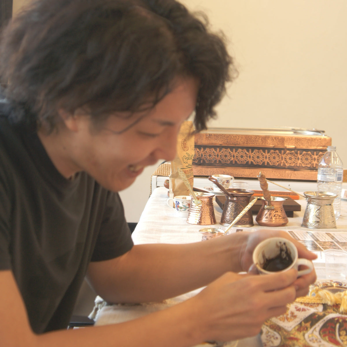 Guest smiling into a Turkish coffee cup during a coffee fortune reading